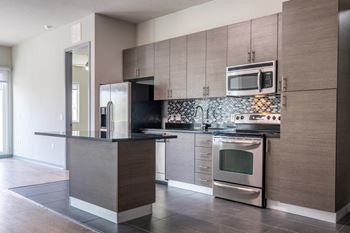 Reveal Heathrow apartments kitchen with custom cabinetry and stainless appliances
